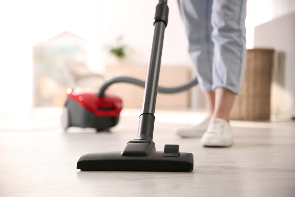 Young,Woman,Using,Vacuum,Cleaner,At,Home,,Closeup