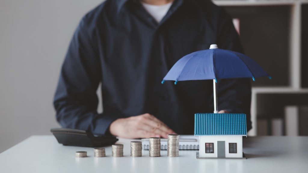 Individuals holding small umbrellas and model homes, housing ins