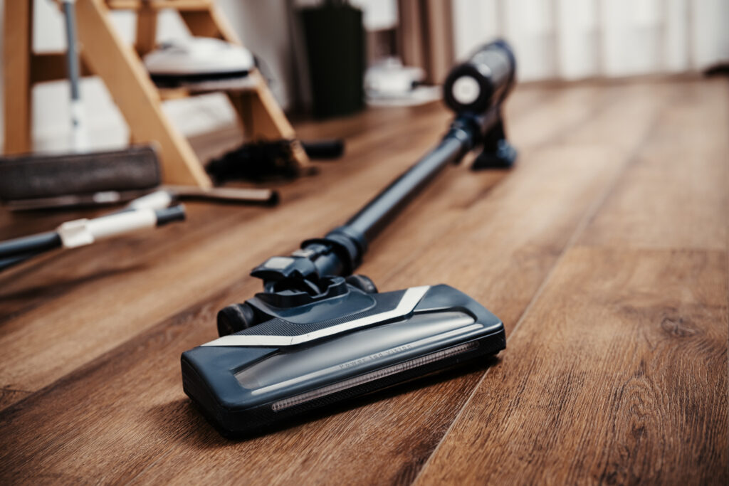 Vacuum cleaner on wooden floor in house. Modern device for domestic housework. Technology, housekeeping and lifestyle concept