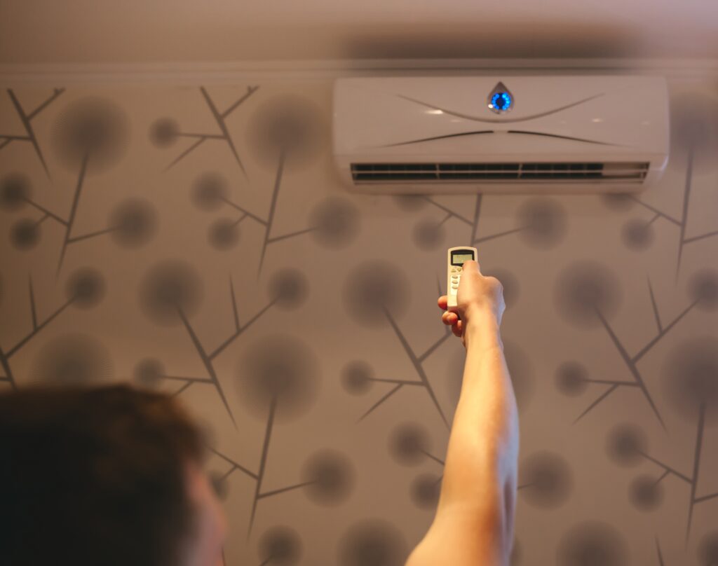 person-adjusting-air-conditioner-with-remote-contr-2026-03-09-06-36-04-utc